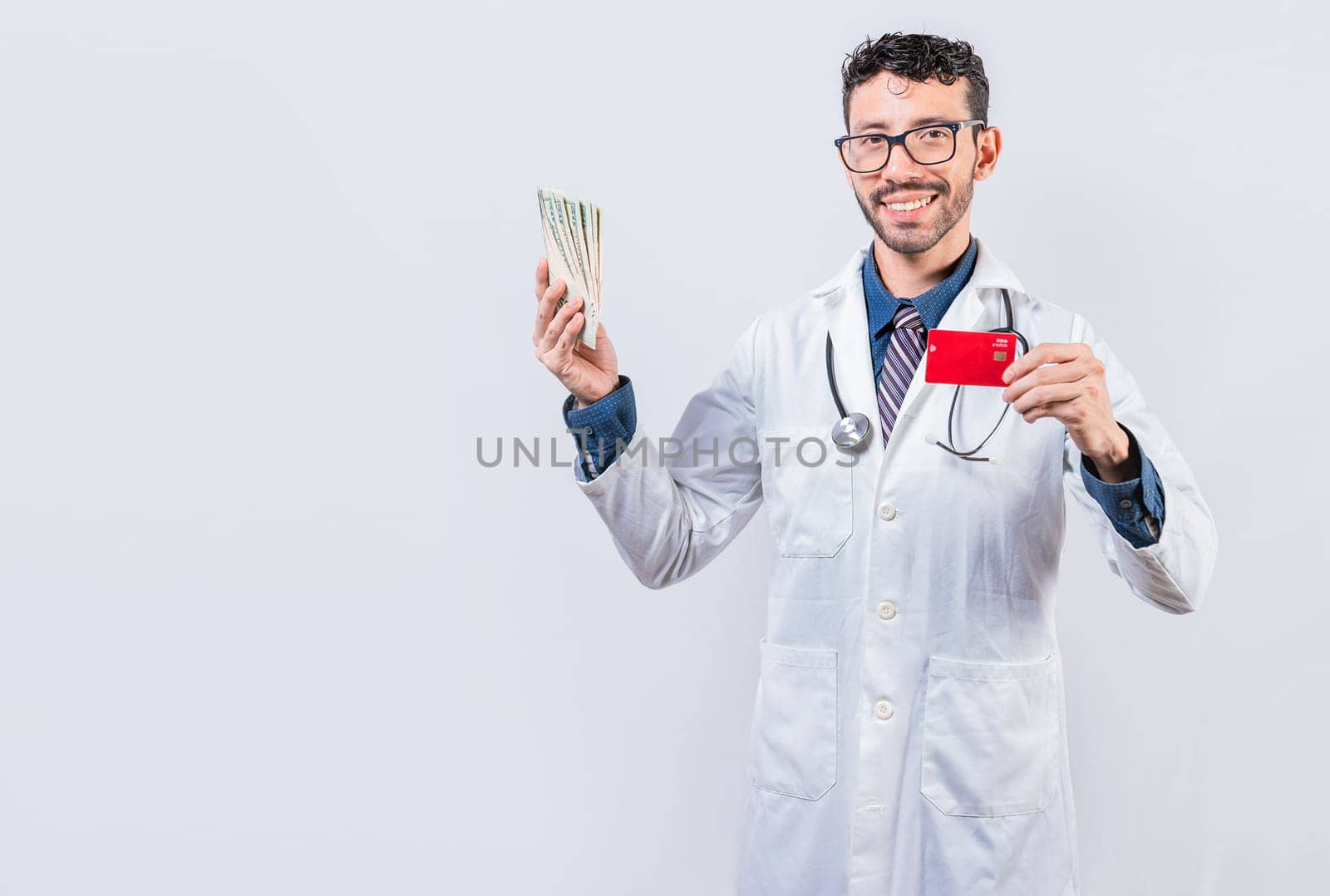 Happy young doctor holding credit card and money isolated. Handsome doctor holding money and credit cards isolated