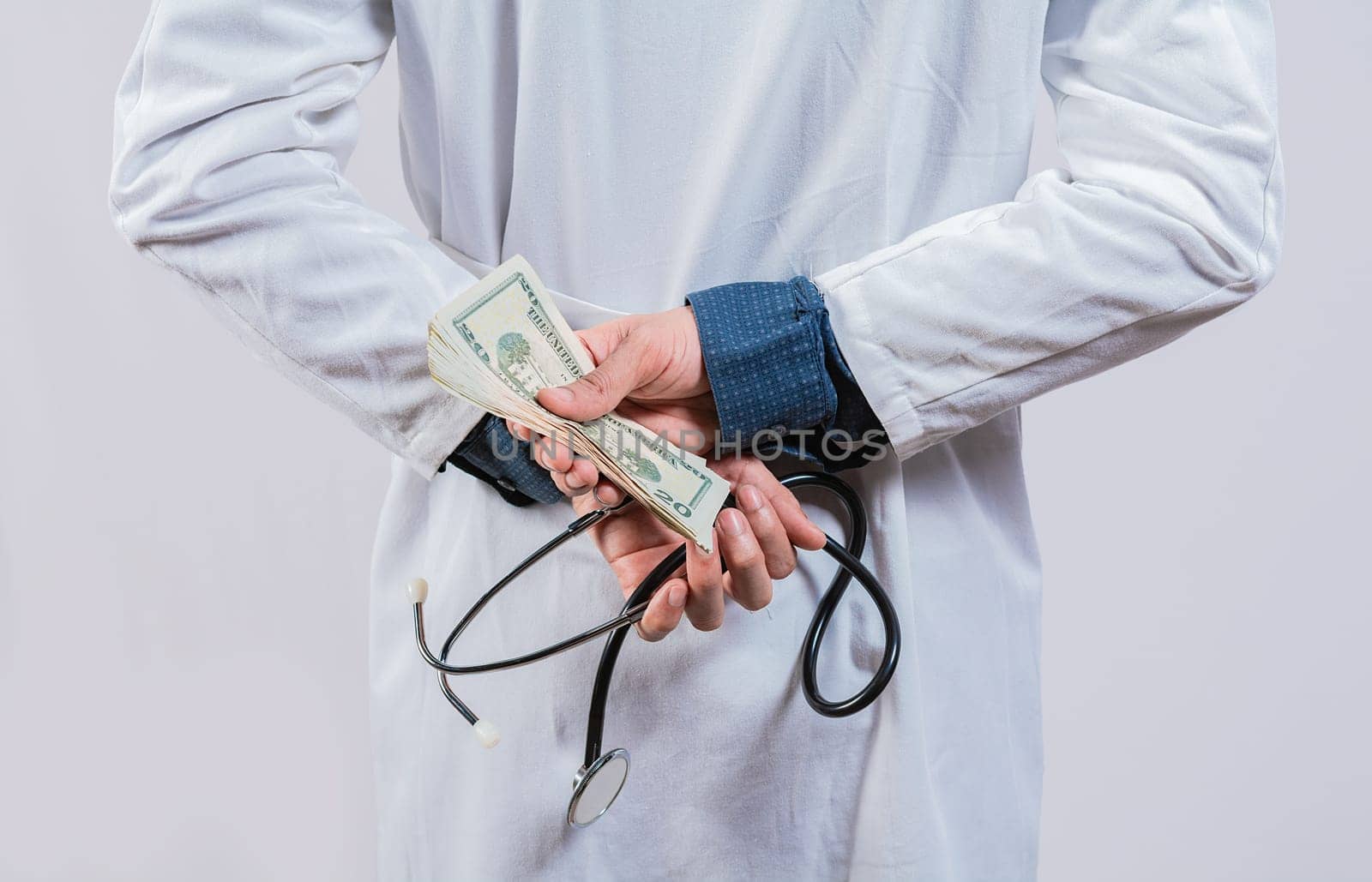 Medical corruption and bribery concept. Corrupt doctor hiding money back, Dishonest doctor hiding money by isaiphoto
