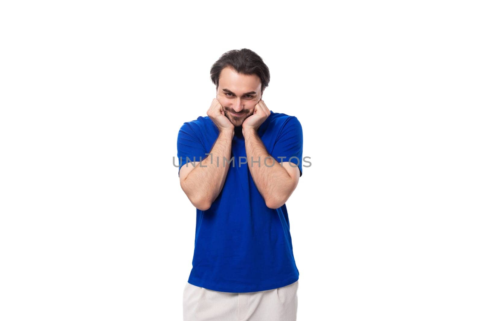 young authentic brunette man with a beard in a blue t-shirt on a white background with copy space.