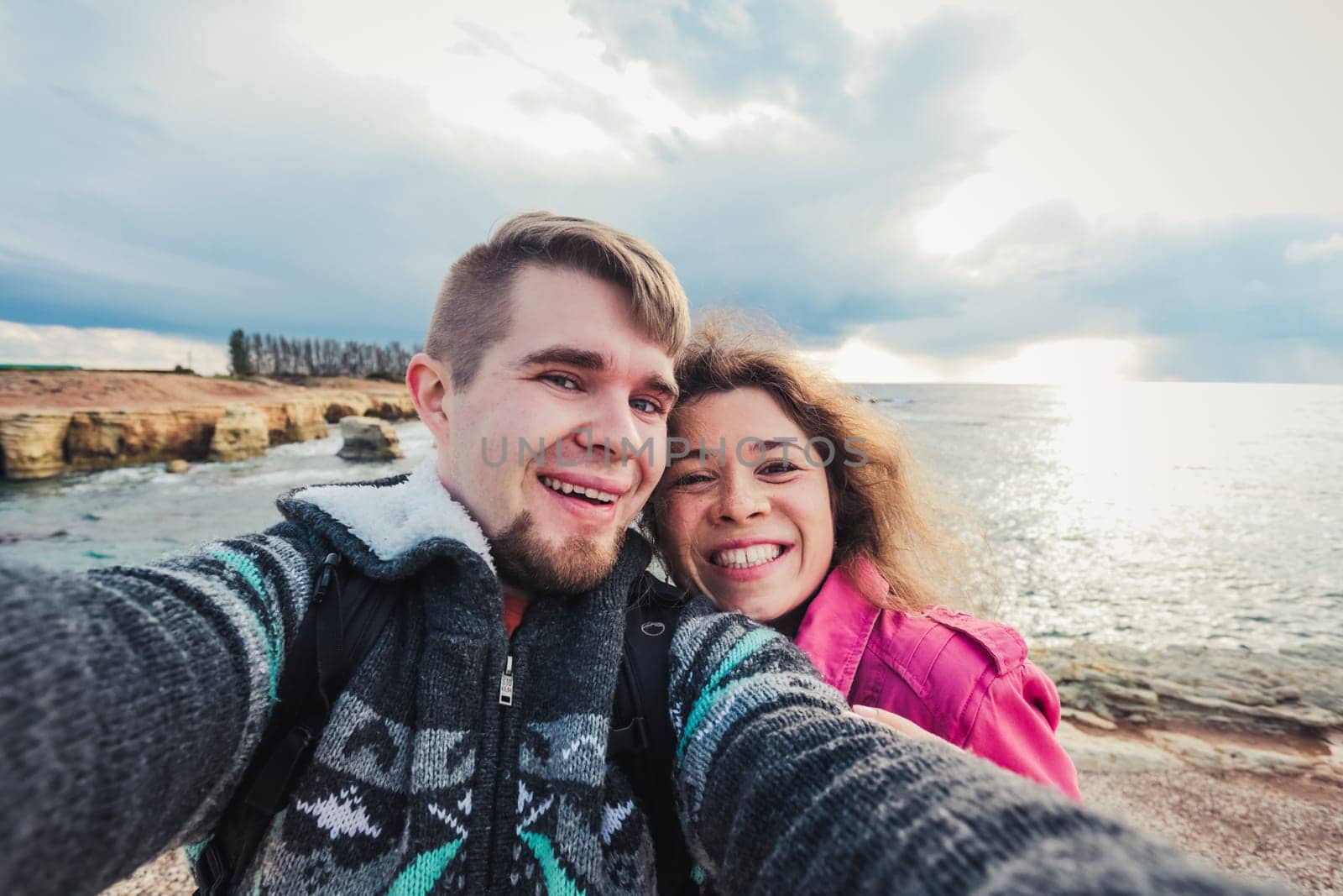 Young happy couple is taking selfie photo on vacation near sea. by Satura86