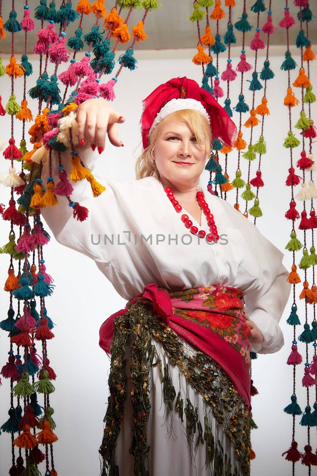 Portrait of cheerful funny adult mature woman solokha. Female model in clothes of national ethnic Slavic style. A stylized Ukrainian, Belarusian or Russian woman poses in a comic photo shoot