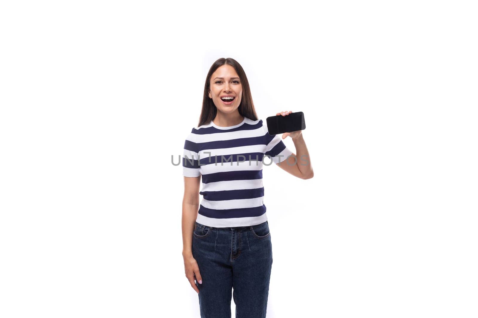 happy young brunette woman with straight hair dressed in a striped t-shirt shows smartphone screen.
