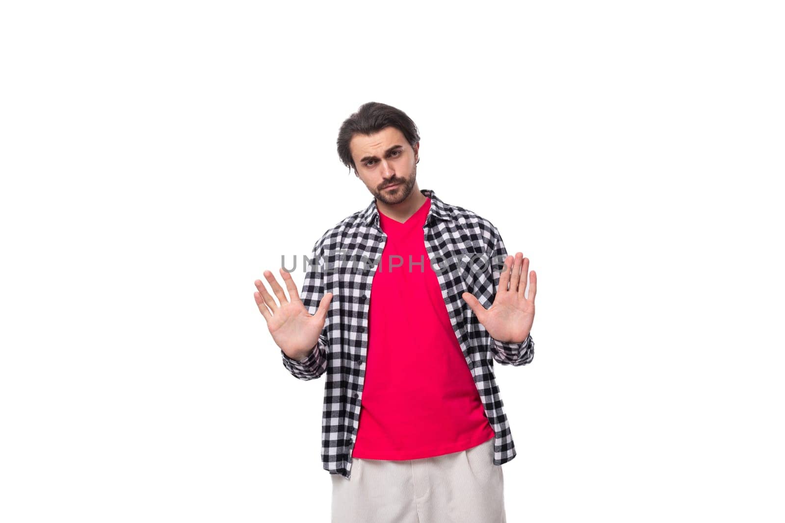 Portrait of a caucasian handsome man with a beard and styled hair stands thoughtfully on a white background with copy space.