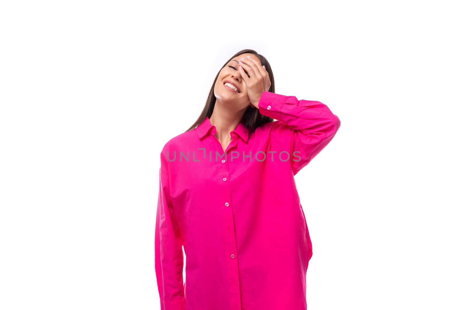 happy positive young brunette lady dressed in a bright pink shirt on a white background.