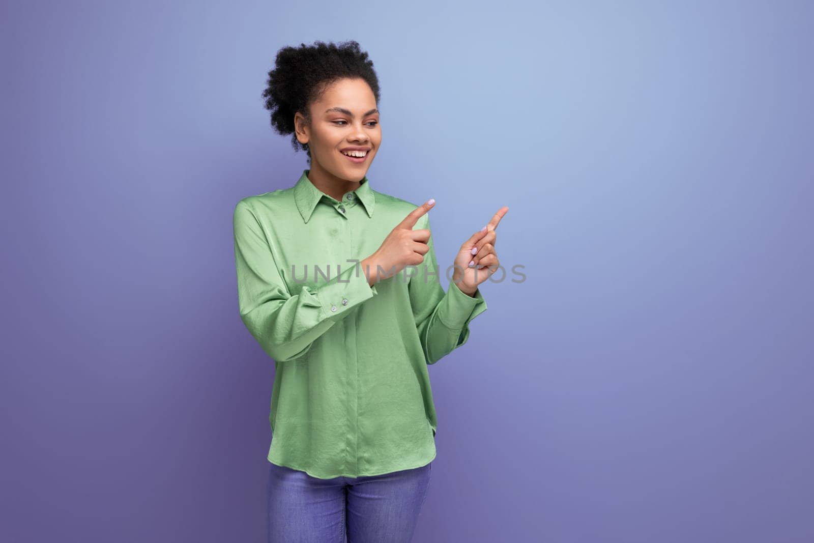 young pretty latin business lady in a green shirt points her hand to the side copy space.