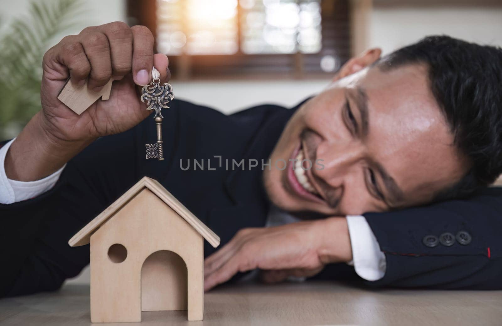 Real estate concept, businessman holding house keys House in hand. Property insurance and security concept. and the symbol of the house by wichayada