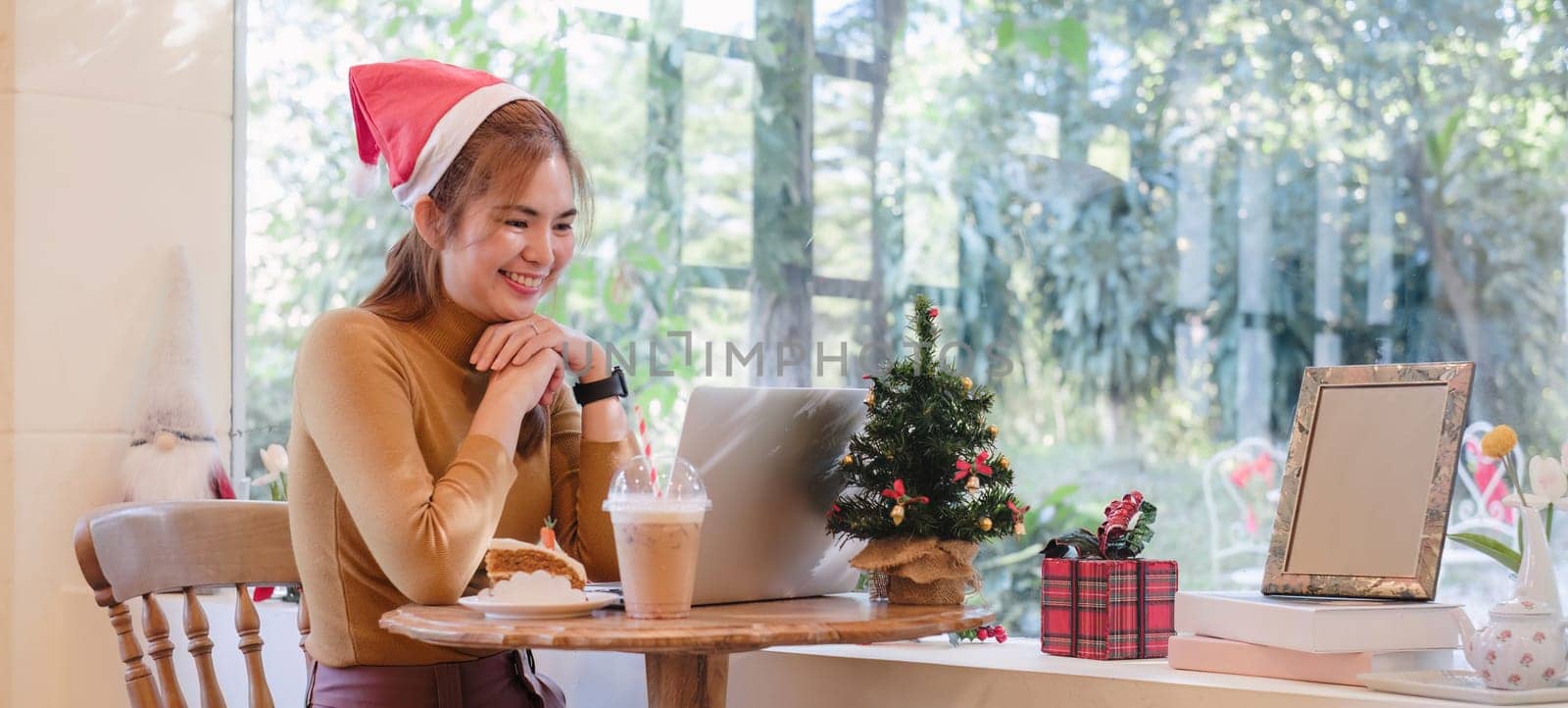A startup employee writes a report on a laptop on Christmas Eve. In an office decorated with colorful bulbs and lights during the Christmas holidays by wichayada