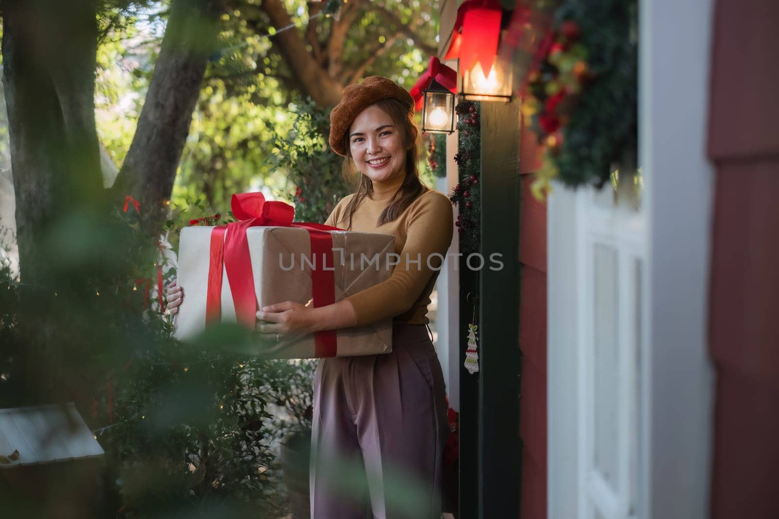 Merry Christmas A beautiful young woman dressed in a Christmas look is decorating the Christmas tree and lights in the house in preparation for a holiday party. Christmas at home by wichayada