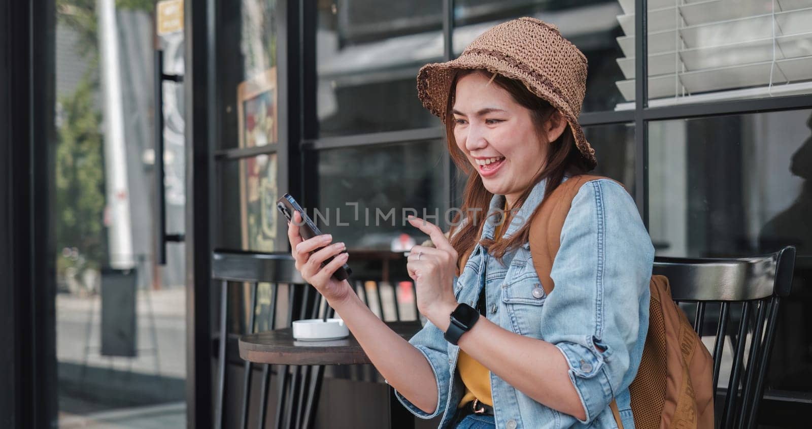 Young Asian tourist walking along city streets and holds a mobile phone on the payment.