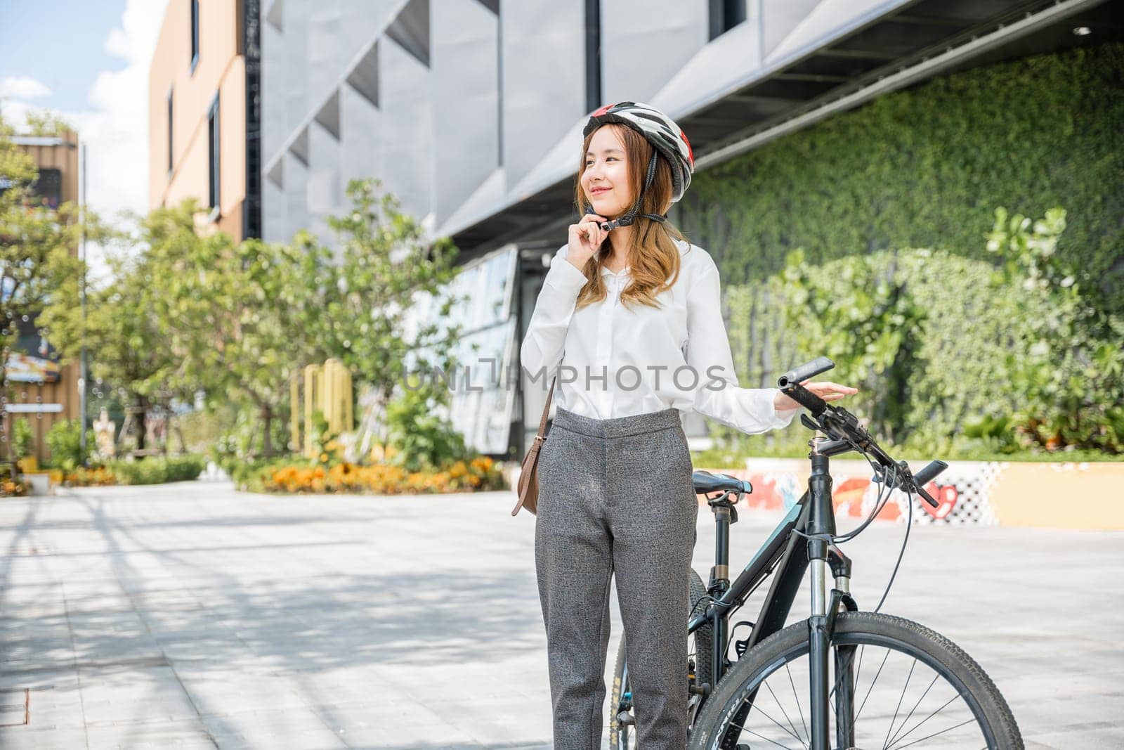 businesswoman putting biking helmet prepared cyclists around building go to work by Sorapop