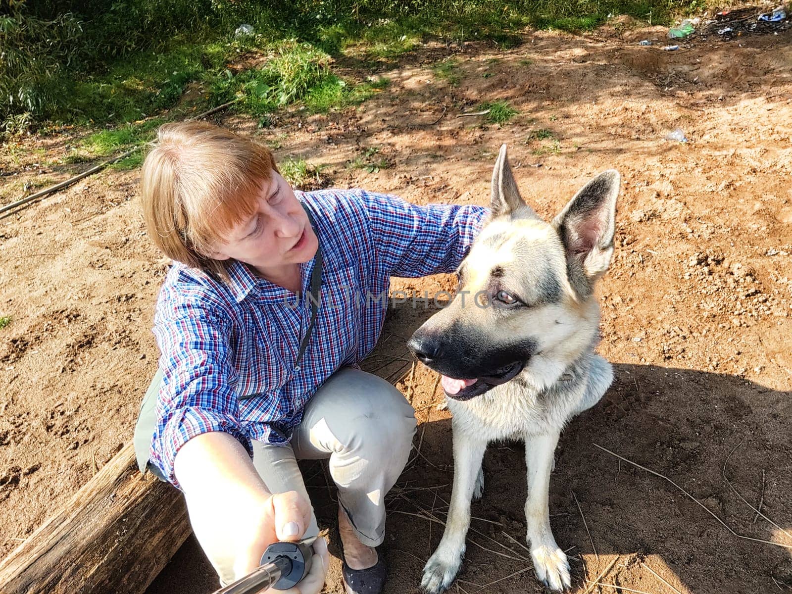 Adult girl with shepherd dog taking selfies in forest. Middle aged woman and big shepherd dog on nature. Friendship, love, communication, fun, hugs