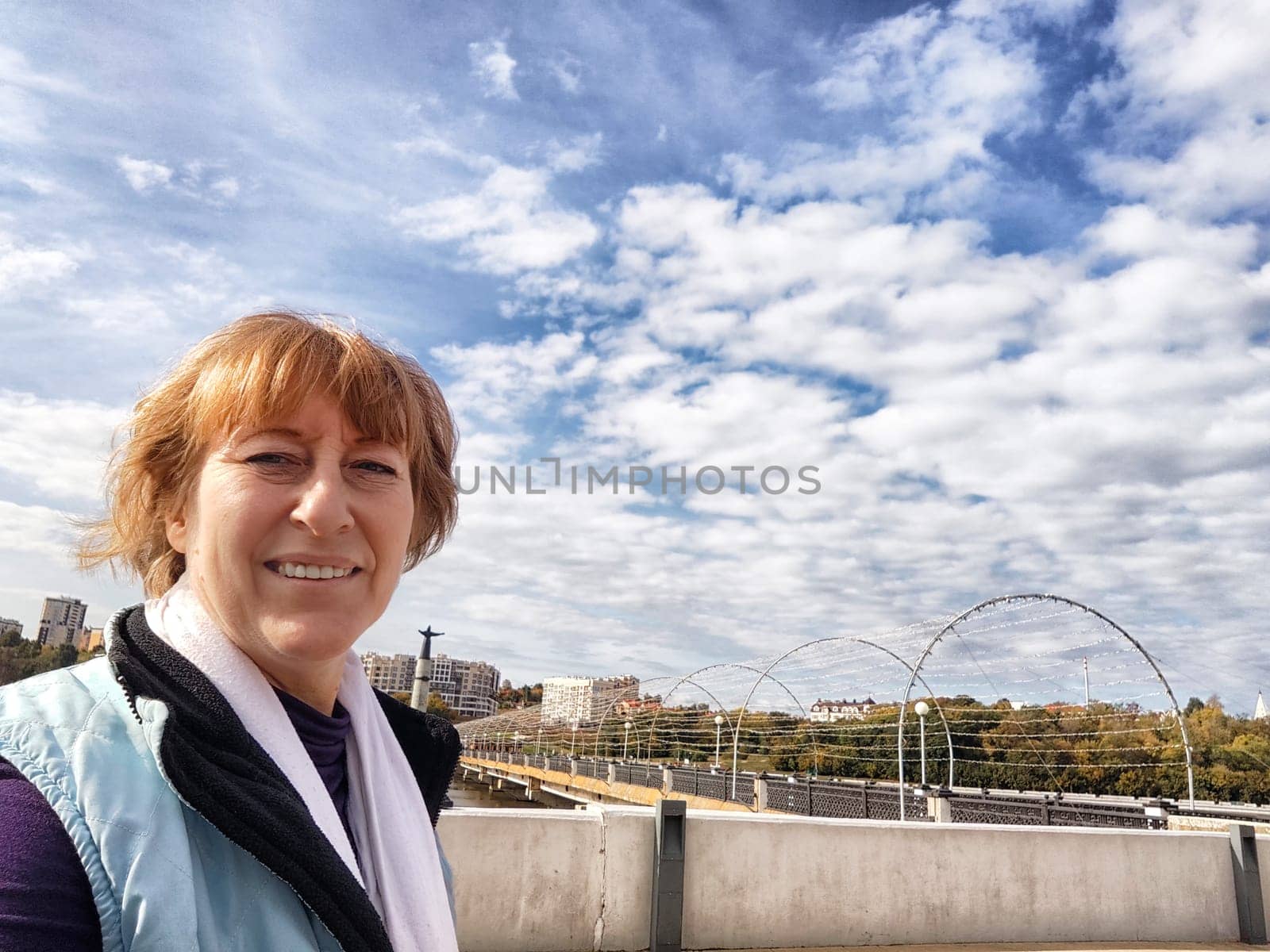 Relaxed mature caucasian female looking at camera and making selfie outside. Positive senior woman against city street background. Adult middle agged girl Blogger posing and taking photo for the internet