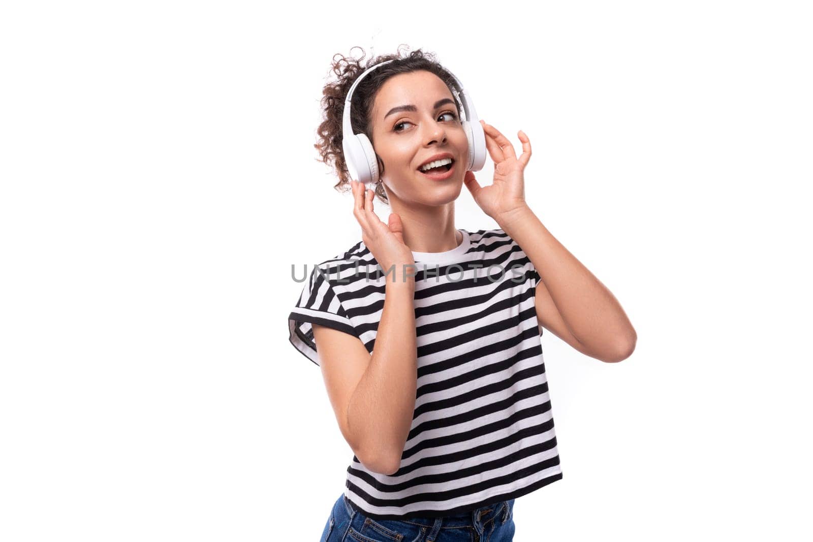 young positive curly brunette woman music lover in a striped casual t-shirt with headphones dancing.