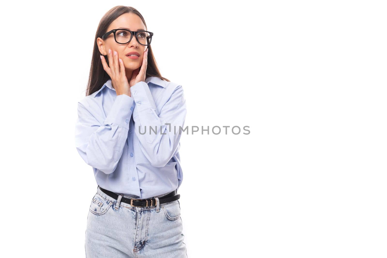 attractive well-groomed young brunette caucasian woman in glasses is dressed in a sky blue shirt on a white background with copy space.