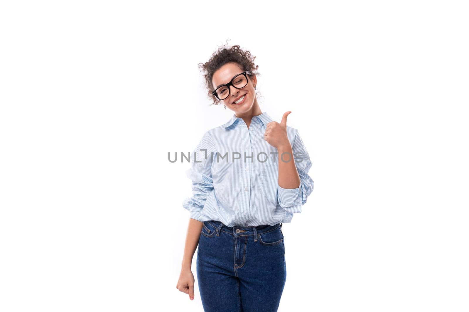 smart stylish young brunette curly young employee of the company woman dressed in a light blue shirt on the background with copy space by TRMK