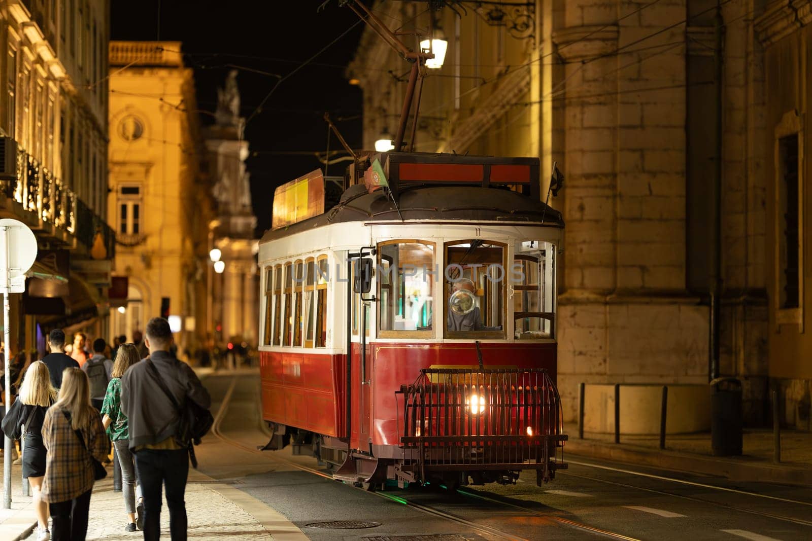 Lisbon, Portugal - red trolley car traveling down a street at nigth by Studia72
