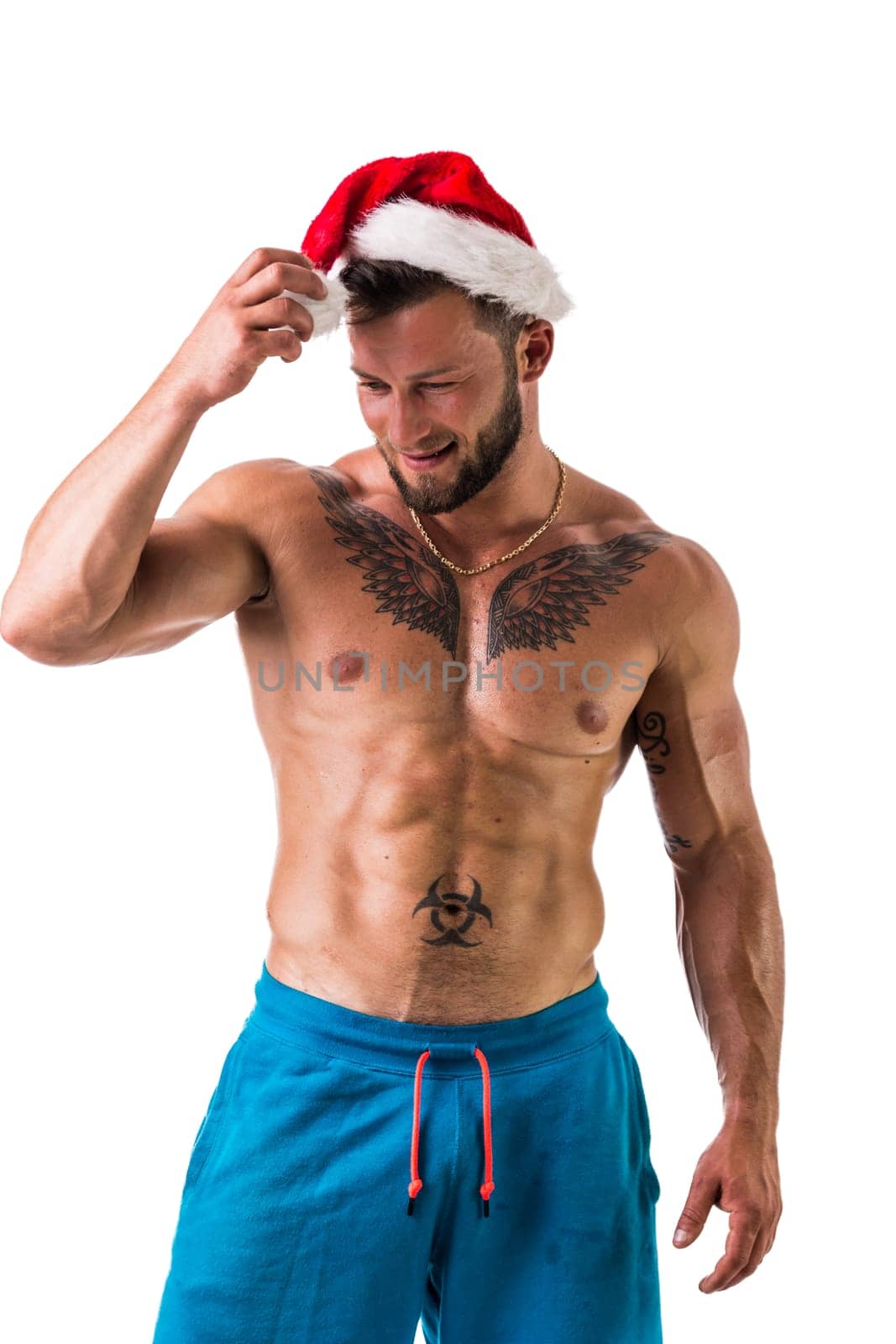 Christmas season: muscular bodybuilder shirtless wearing Santa Claus red hat by artofphoto