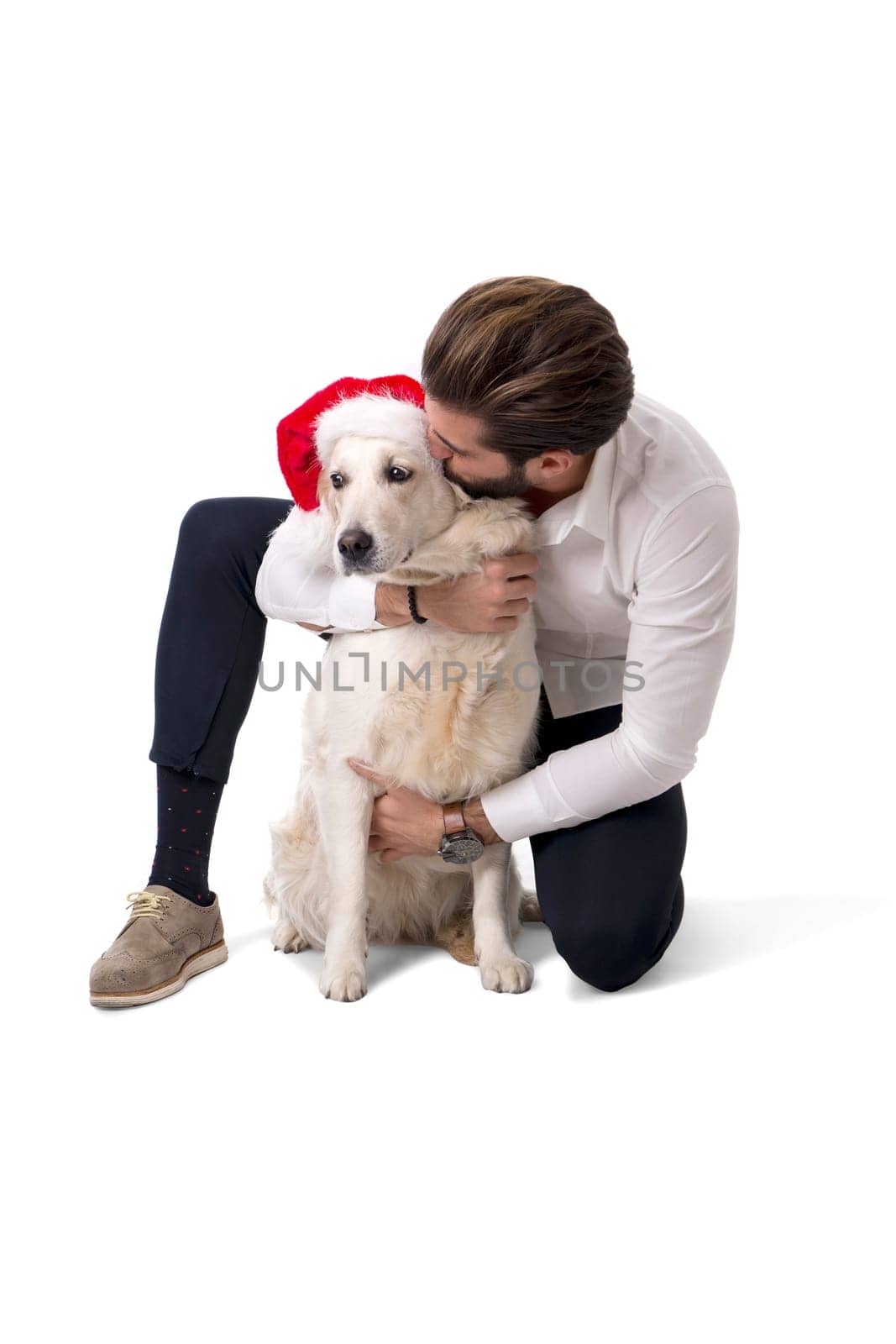 Handsome young man with labrador white dog wearing Santa Claus red hat for Christmas to celebrate the season, on white background in studio