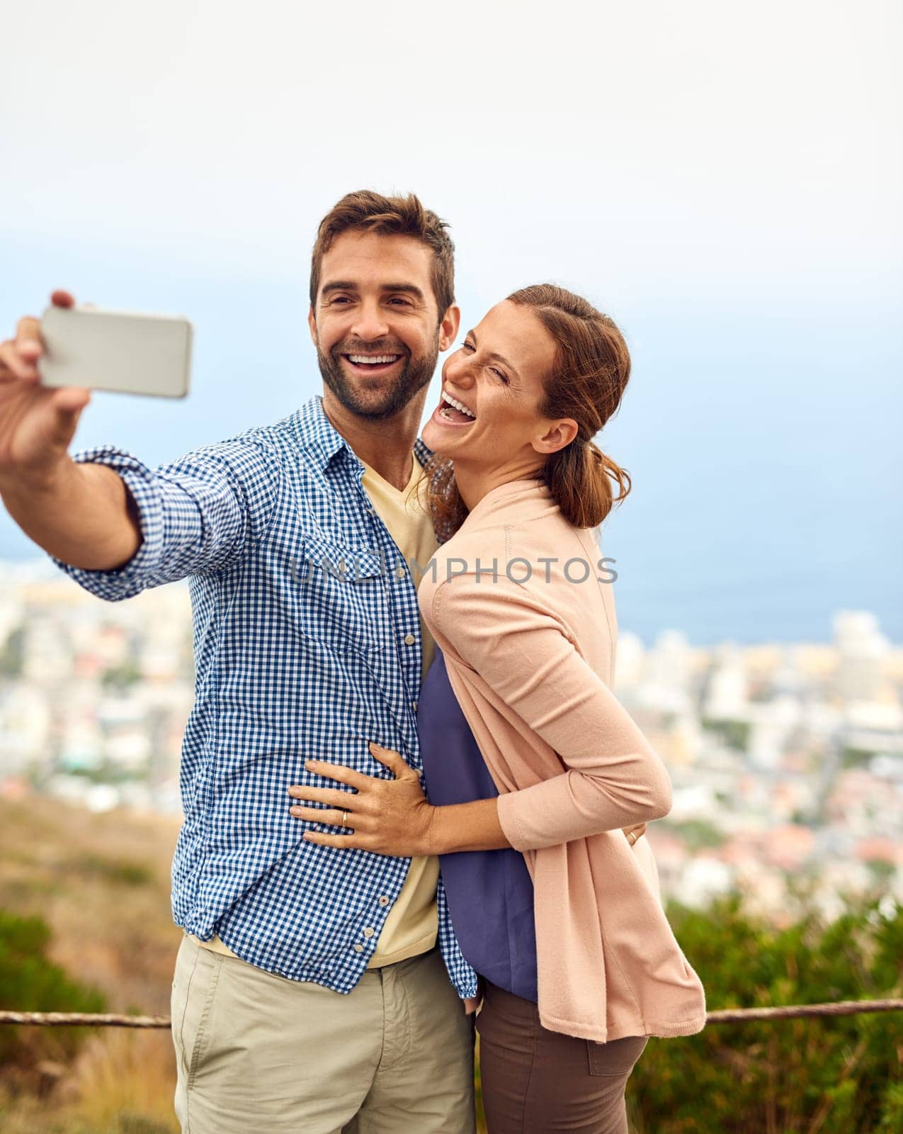 Couple, hug and selfie on vacation, laughing and outdoors on adventure, love and memories for social media. Happy people, smartphone and bonding or technology, travel and holiday or free on date.