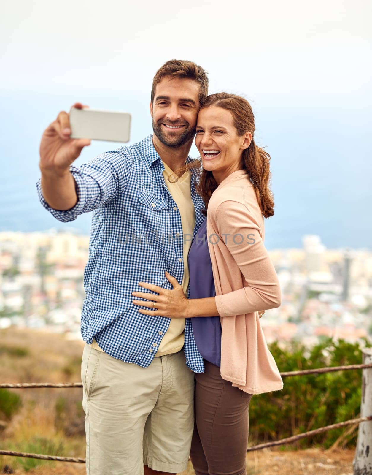 Couple, hug and selfie on phone, love and outdoors on vacation, laughing and memories for social media. Happy people, smartphone and adventure or technology, travel and humor on holiday, fun and joke.