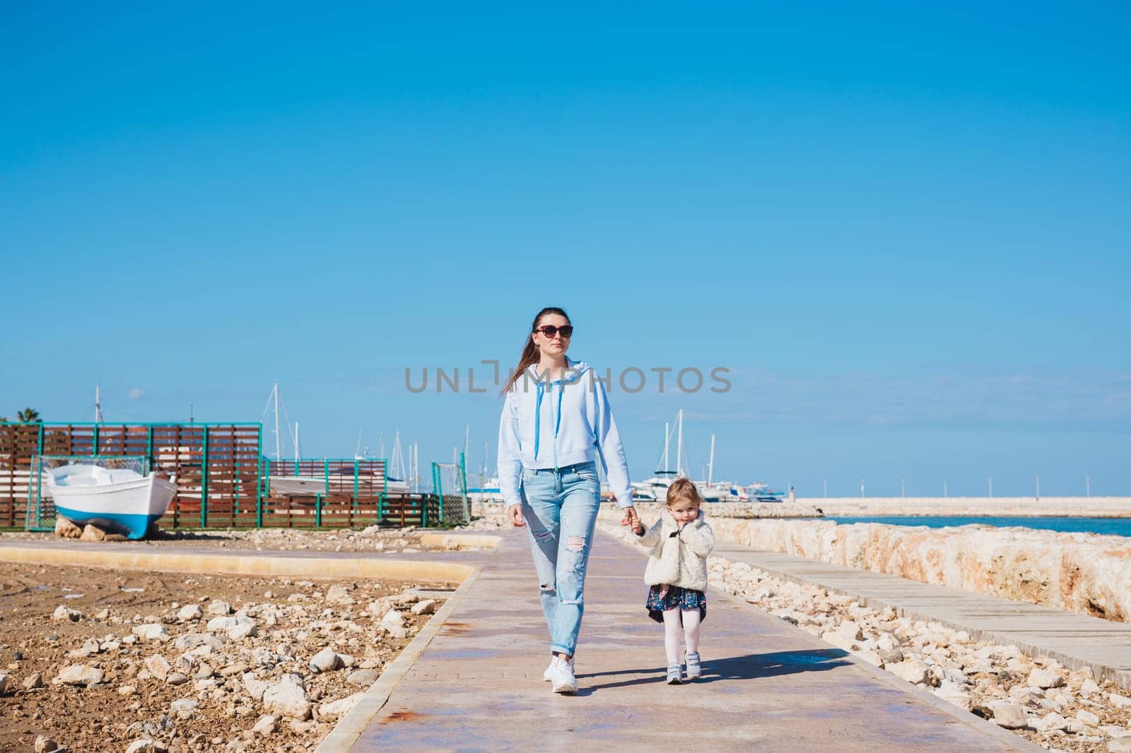 mother and little daughter walking on summer tropical beach