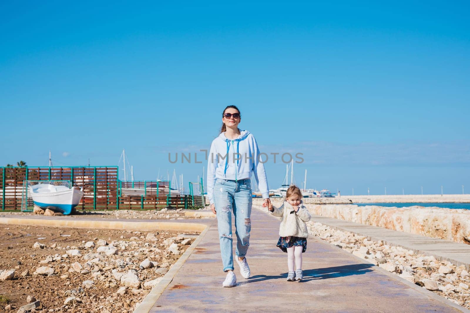 mother and little daughter walking on summer tropical beach