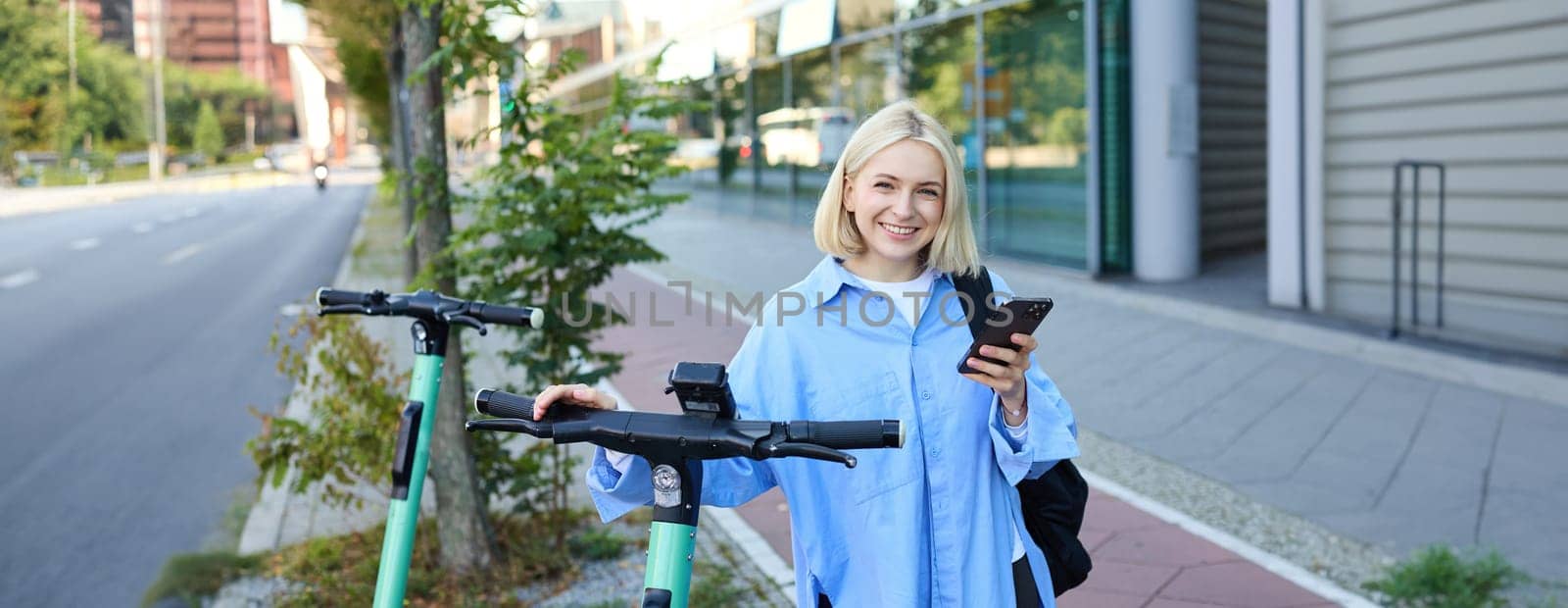 Portrait of young woman, renting a scooter, using mobile phone app to unlock it, using quick ride to get to work, smiling and looking happy by Benzoix