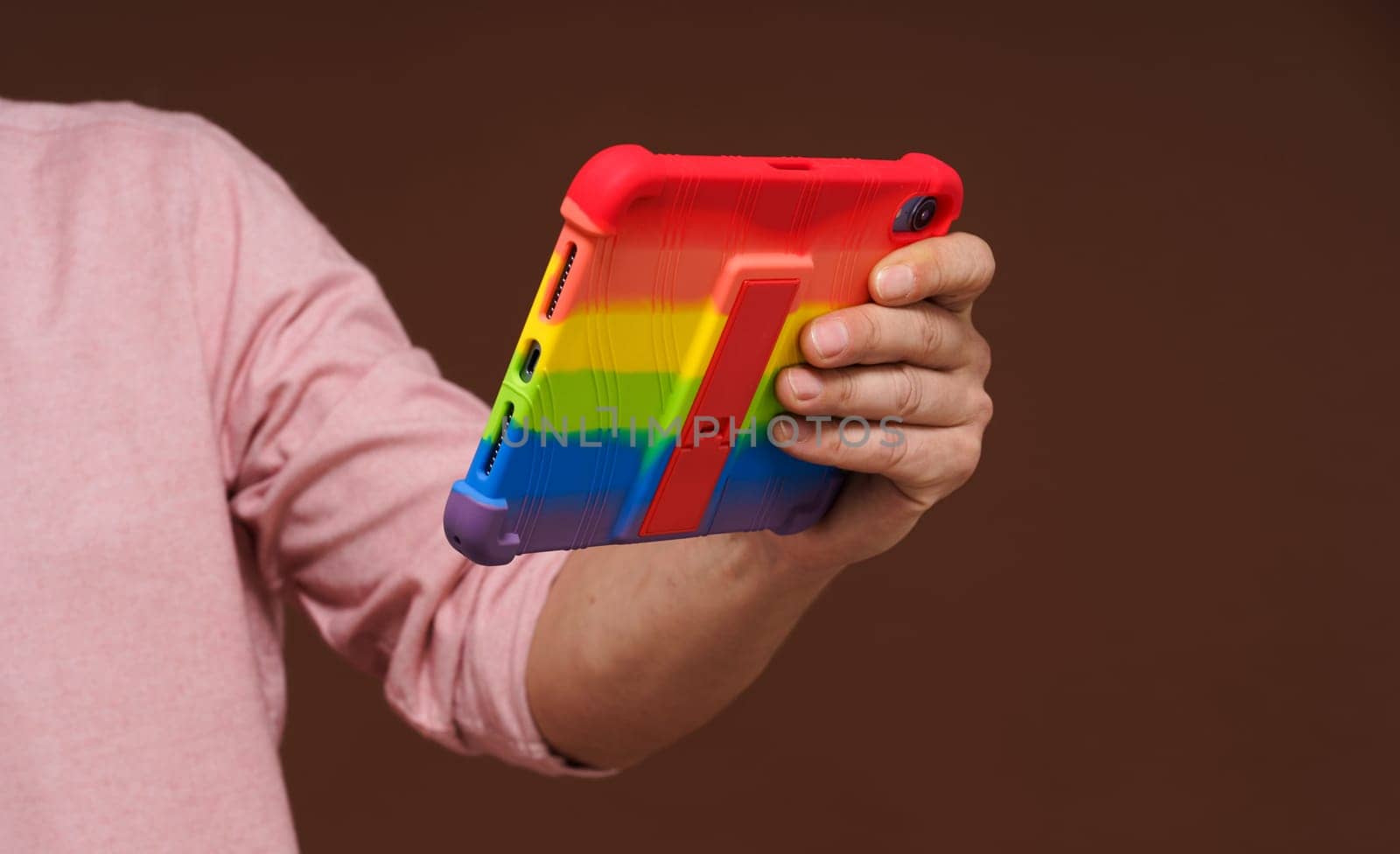 Sign of gay culture and LGBTQ pride representing man's hand holding pocket PC adorned in rainbow colors, Rainbow symbolism reflects diversity and inclusivity of LGBTQ community. by LipikStockMedia