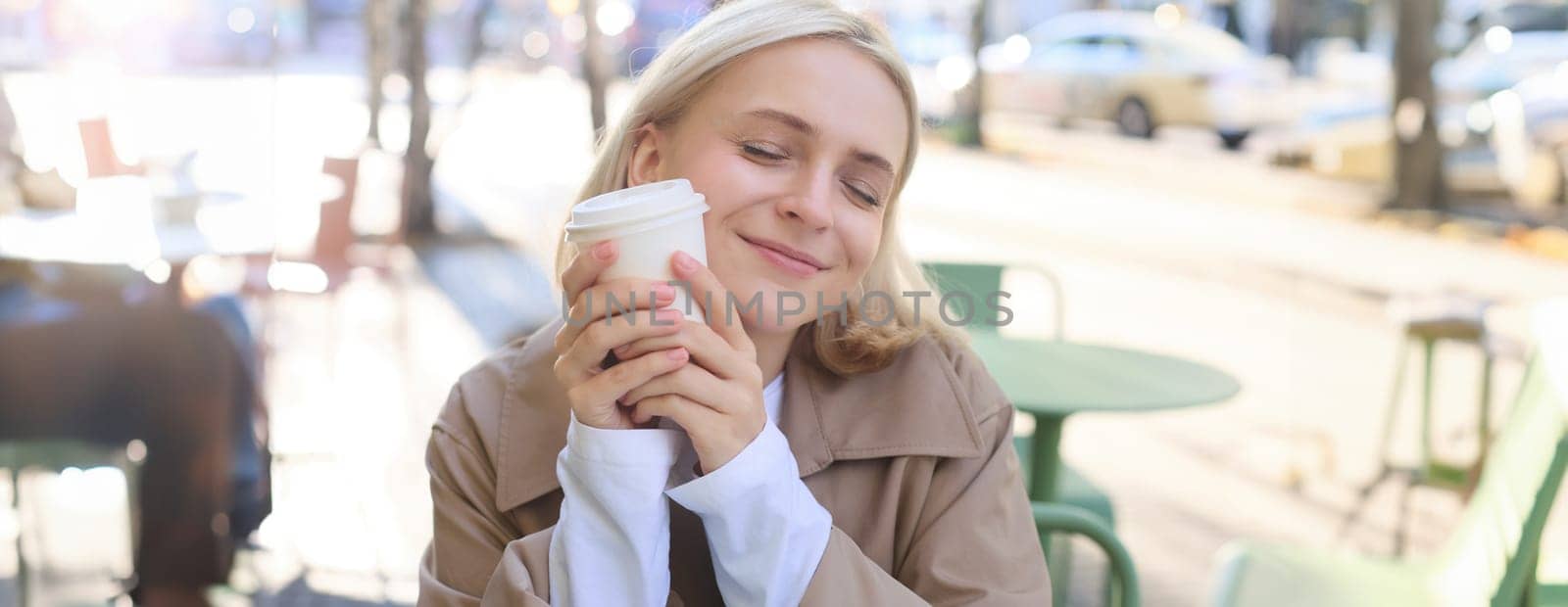 Close up portrait of smiling, happy beautiful european woman, sitting in cafe and enjoying cup of coffee, drinking beverage, enjoying bright sunny day outdoors by Benzoix
