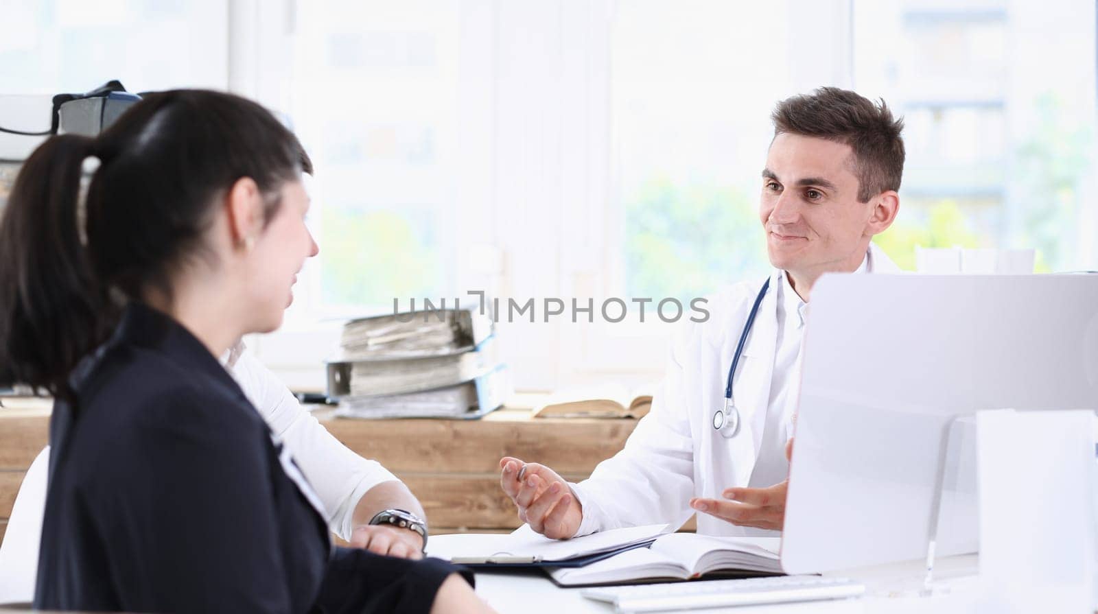 Male family doctor listen carefully young couple in office portrait. Motherhood and child delivery new life or abortion therapeutist reception service physical hospital and clinic concept
