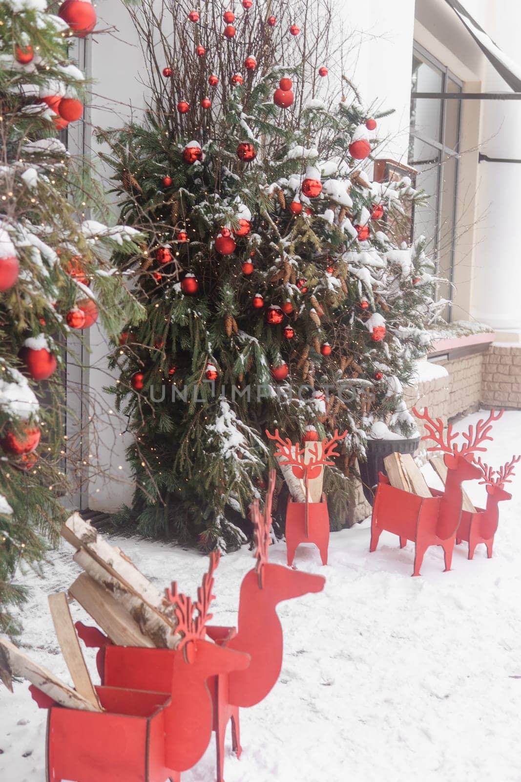 Christmas trees decorated with red balloons in front of the entrance to the cafe. Street Christmas decorations. by Annu1tochka