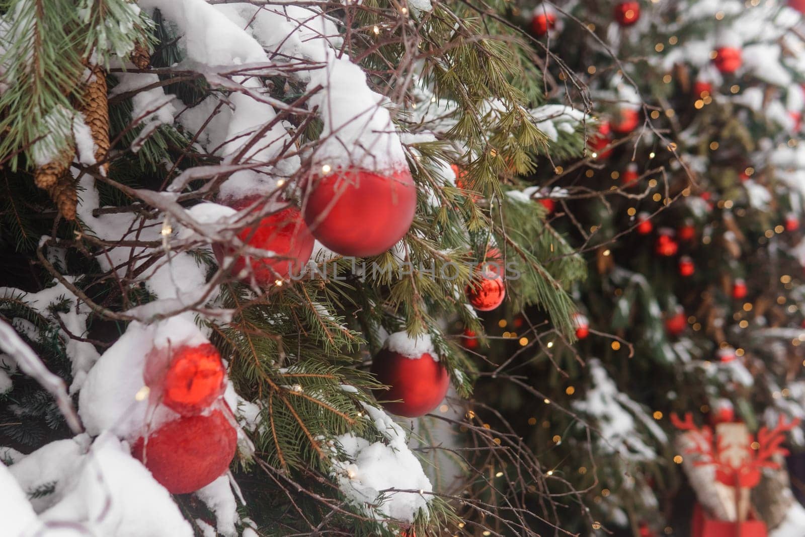 Christmas trees decorated with red balloons in front of the entrance to the cafe. Street Christmas decorations