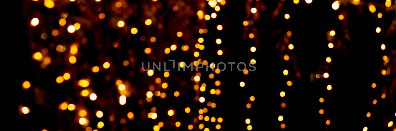 Blurry garland lights on a dark background. Festive Christmas and New Year background. Soft focus.