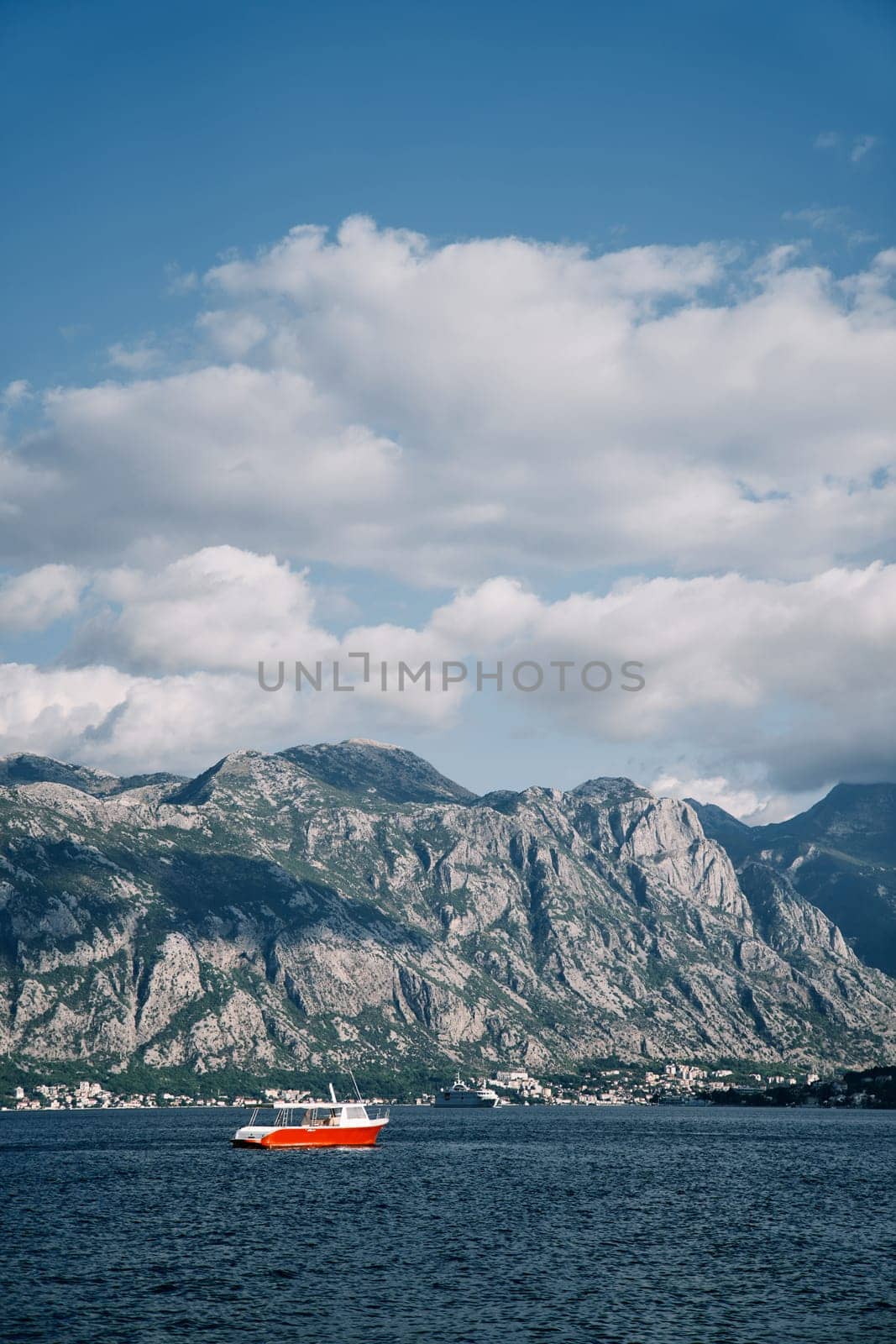 Red excursion boat with a canopy floats on the sea against the backdrop of high mountains. High quality photo