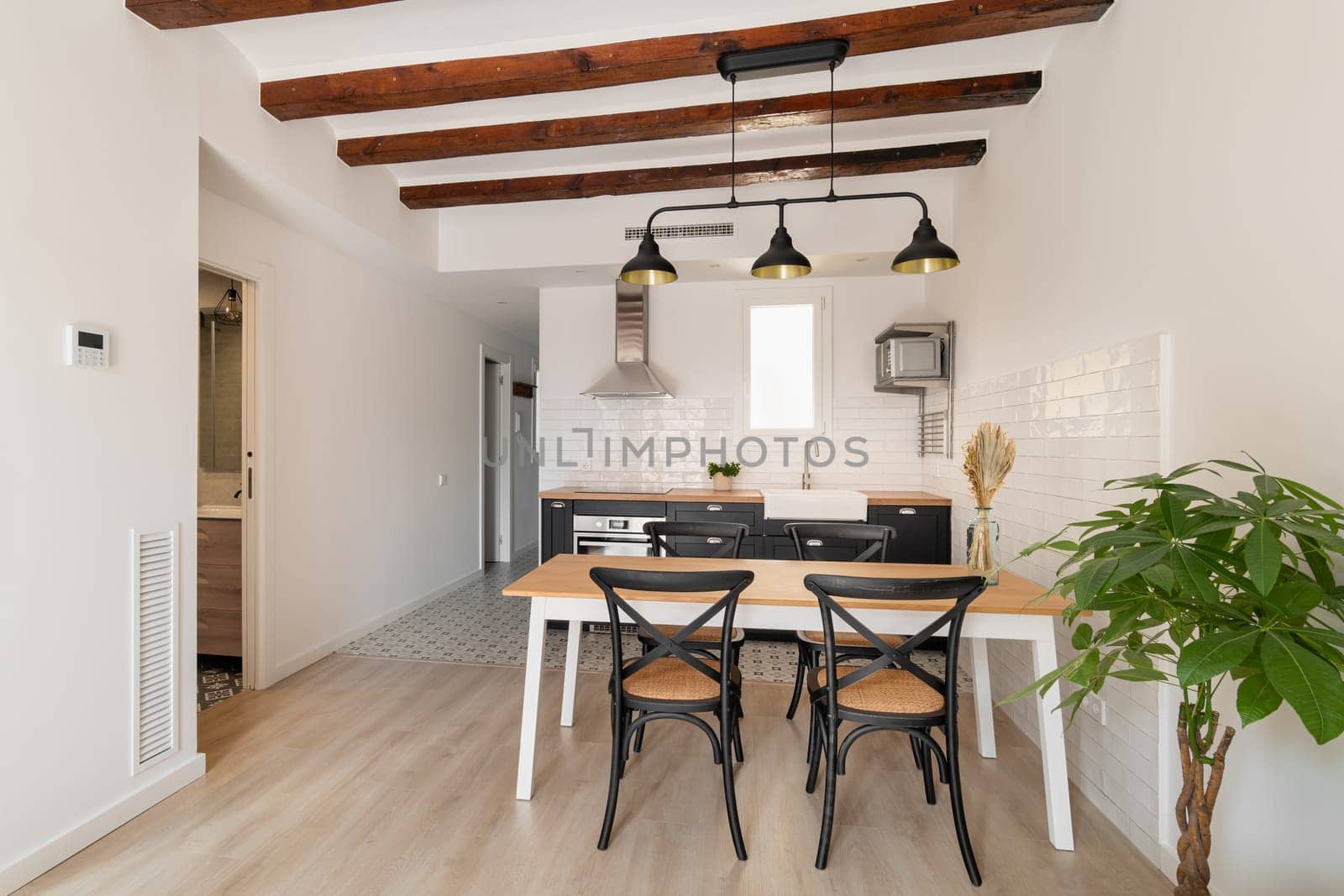 Empty dining table in equipped kitchen area of renovated studio apartment. Simple interior of home residence with place to cook and eat
