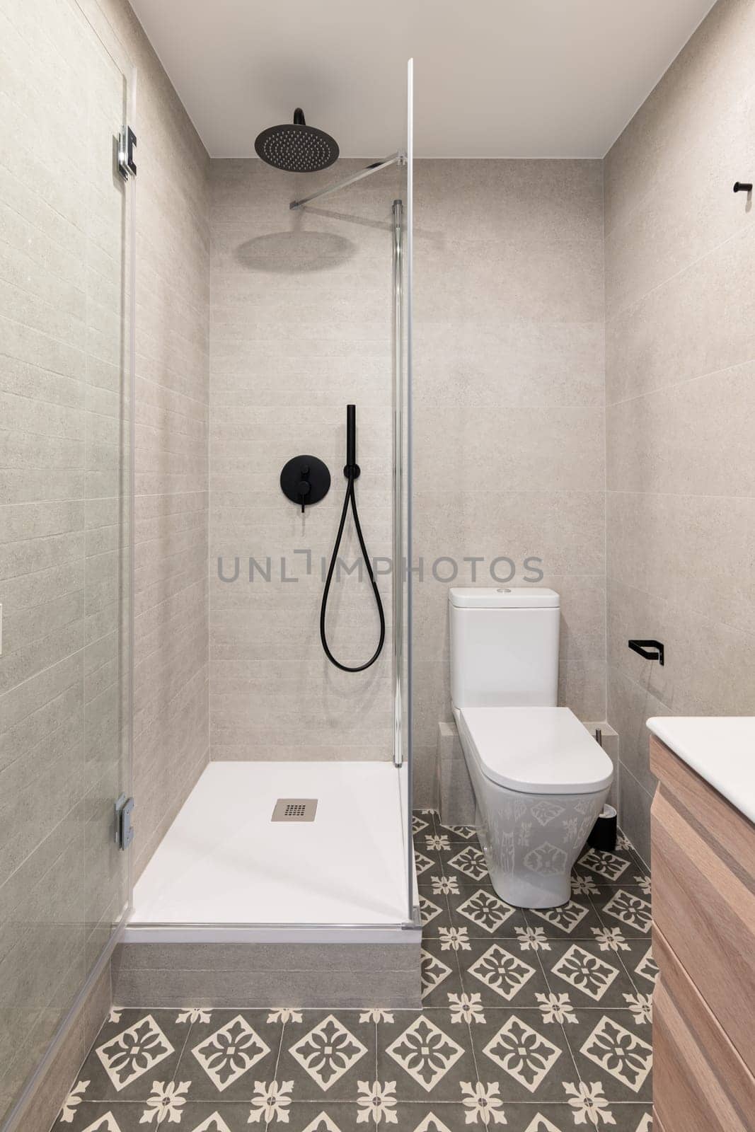 Stylish shower unit and ceramic toilet bowl in small bathroom. Modern equipment for hygiene in hotel room. Ideas for interior design