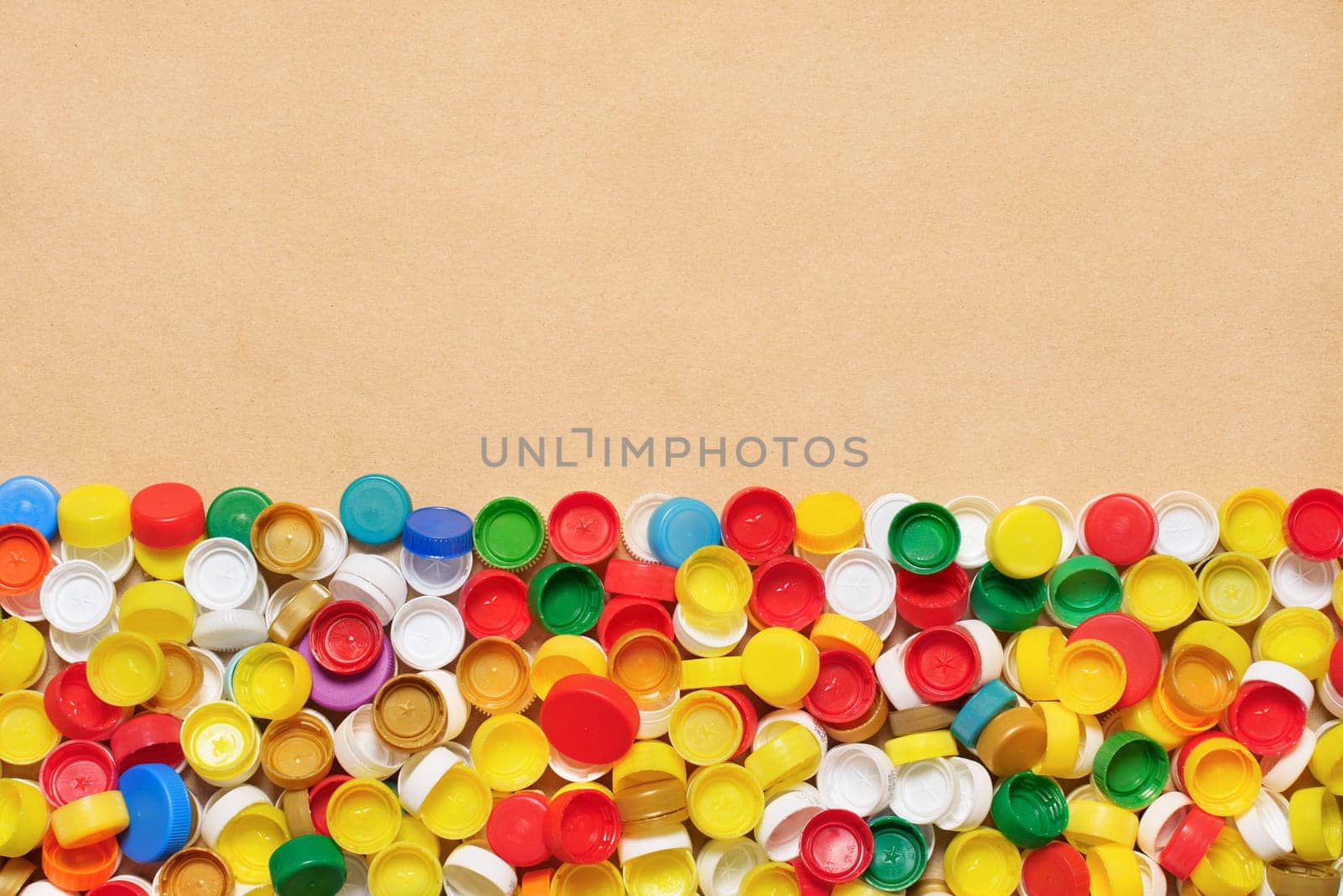 Collection of plastic caps on cardboard background. PET recycling plastic bottle cap recycling bottle cap PET plastic lids on recycling background. Recyclable materials. Sorting waste separation.