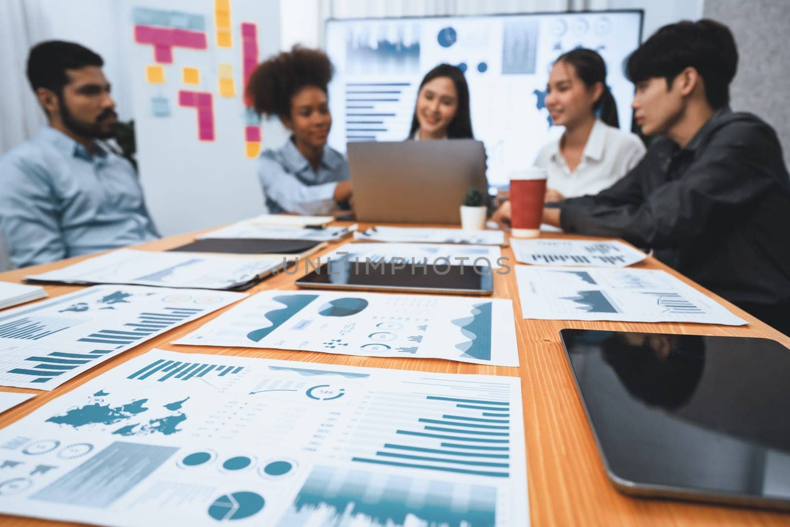 Focus financial dashboard paper showing graphs and chart with blurred background of diverse business people analyzing business data by BI Fintech technology for business marketing indication. Concord