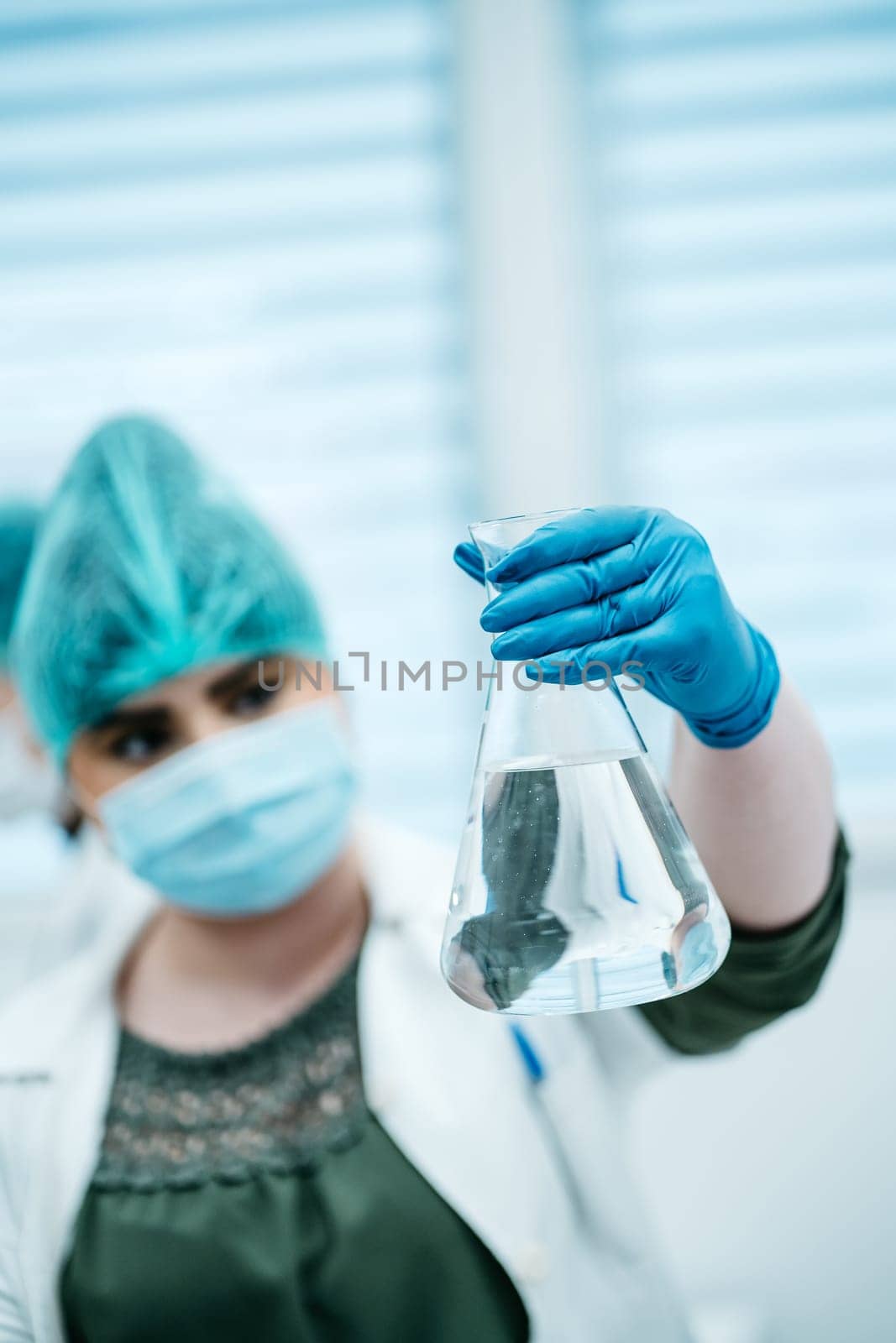Woman holds medical flask with clear liquid by Praximon