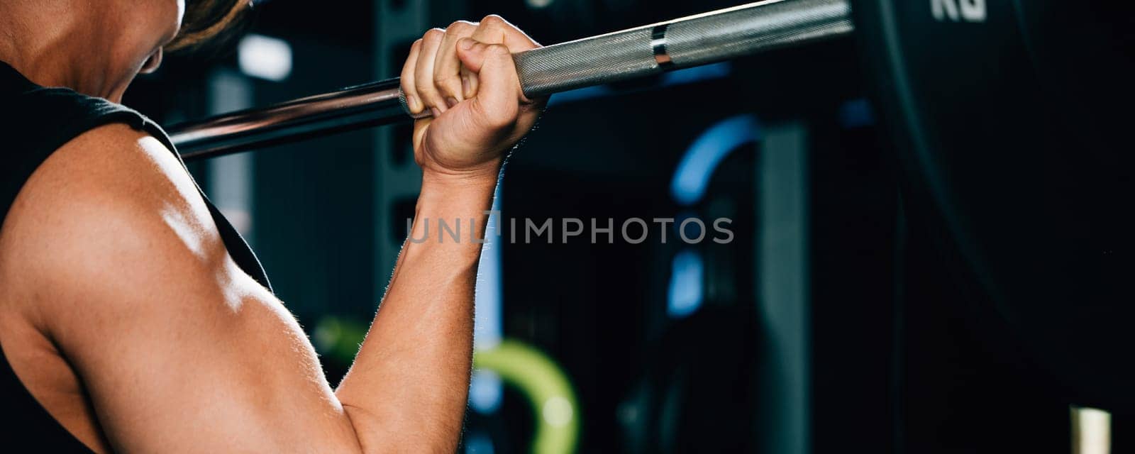 An attractive male weightlifter with a muscular body, lifting a heavy barbell for a strength-building workout in the gym. power lifting training concept