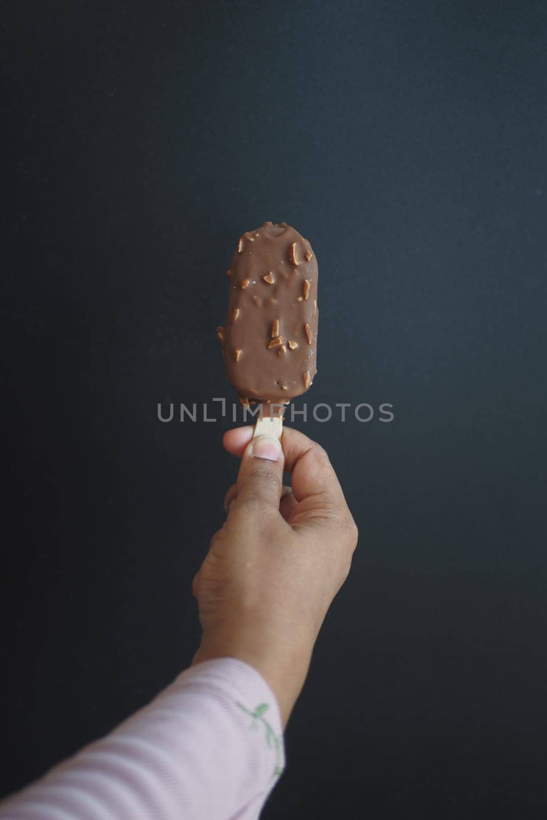 Hand holding melting ice cream on dark background by towfiq007