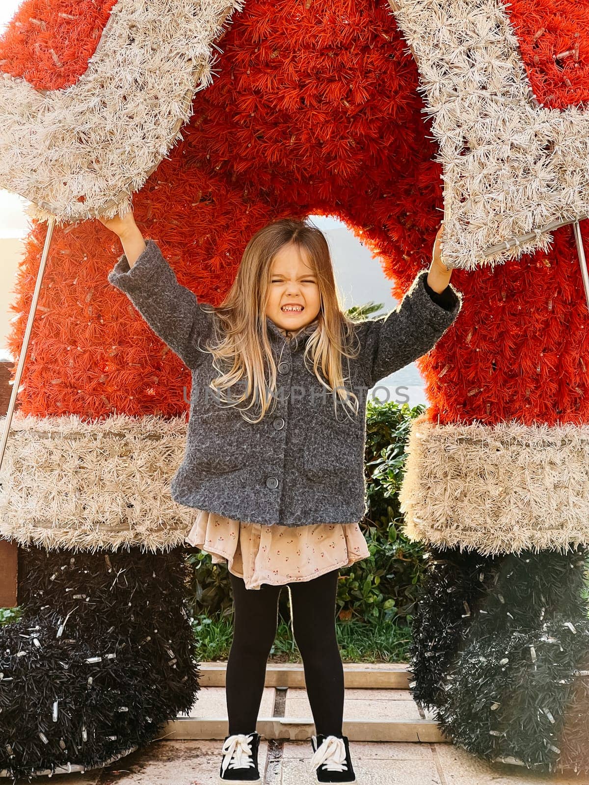 Little girl stands near a big fluffy figure of Santa Claus. High quality photo