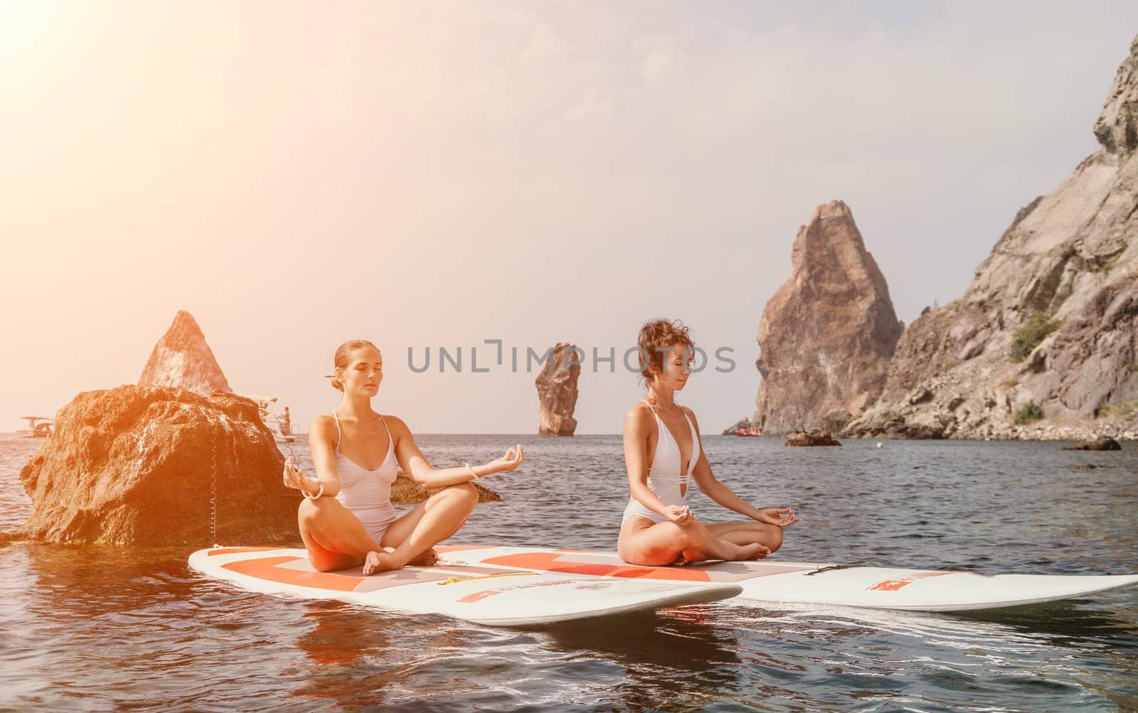 Woman sup yoga. Happy sporty woman practising yoga pilates on paddle sup surfboard. Female stretching doing workout on sea water. Modern individual female hipster outdoor summer sport activity. by panophotograph