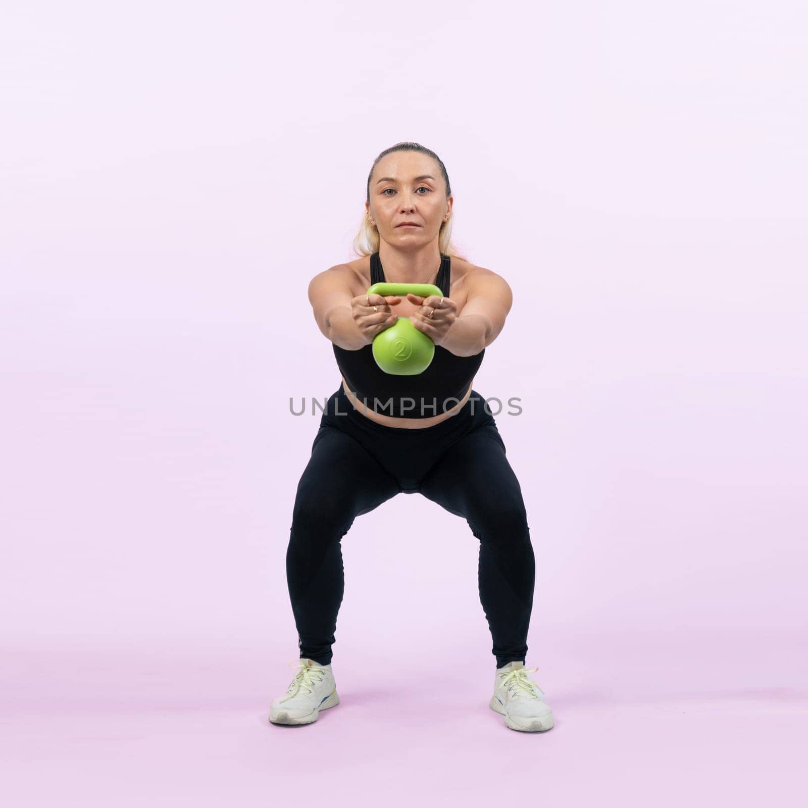 Full body length shot athletic senior woman doing squat with weight. Clout by biancoblue