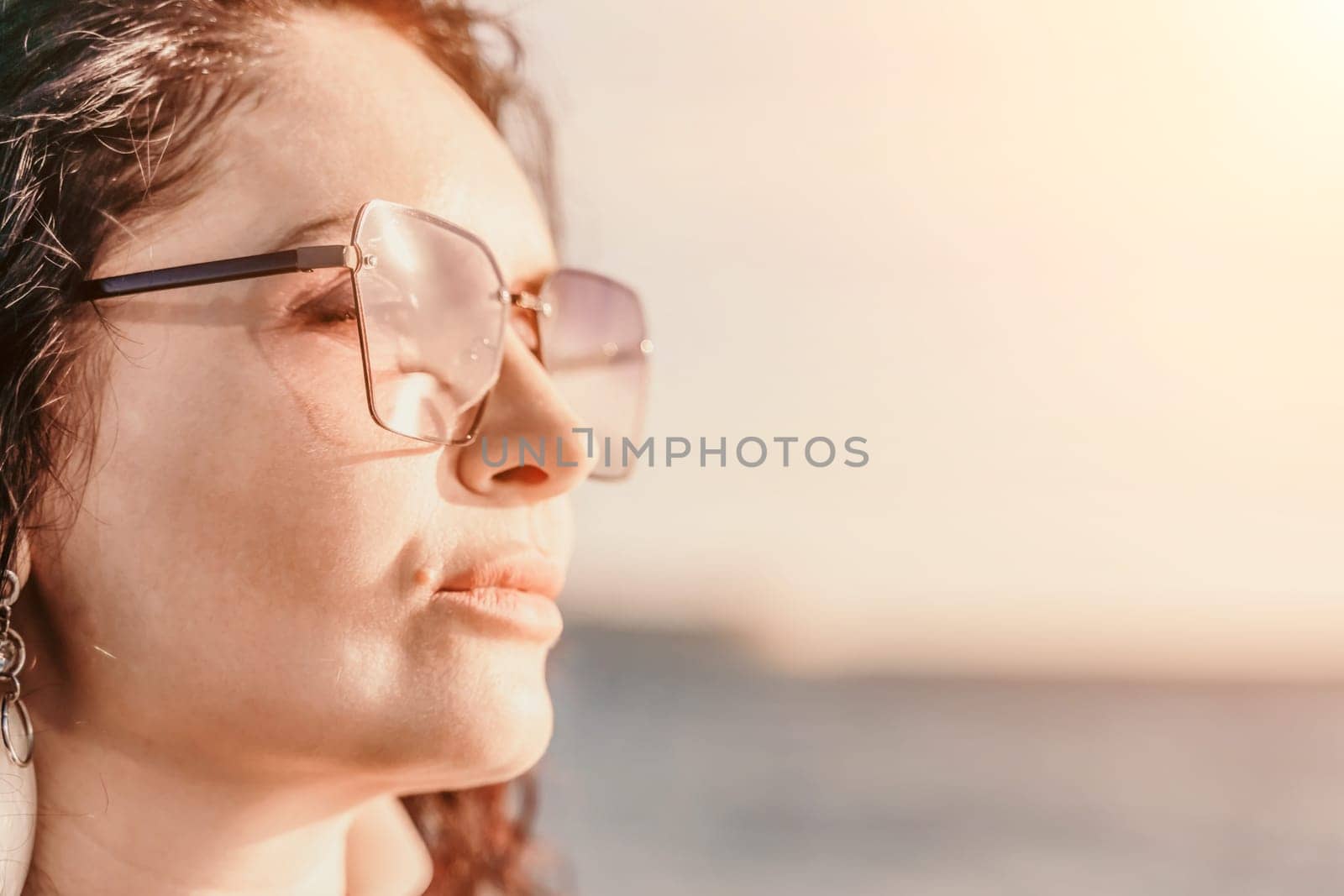 Portrait of a curly woman in glasses on the background of the se by Matiunina