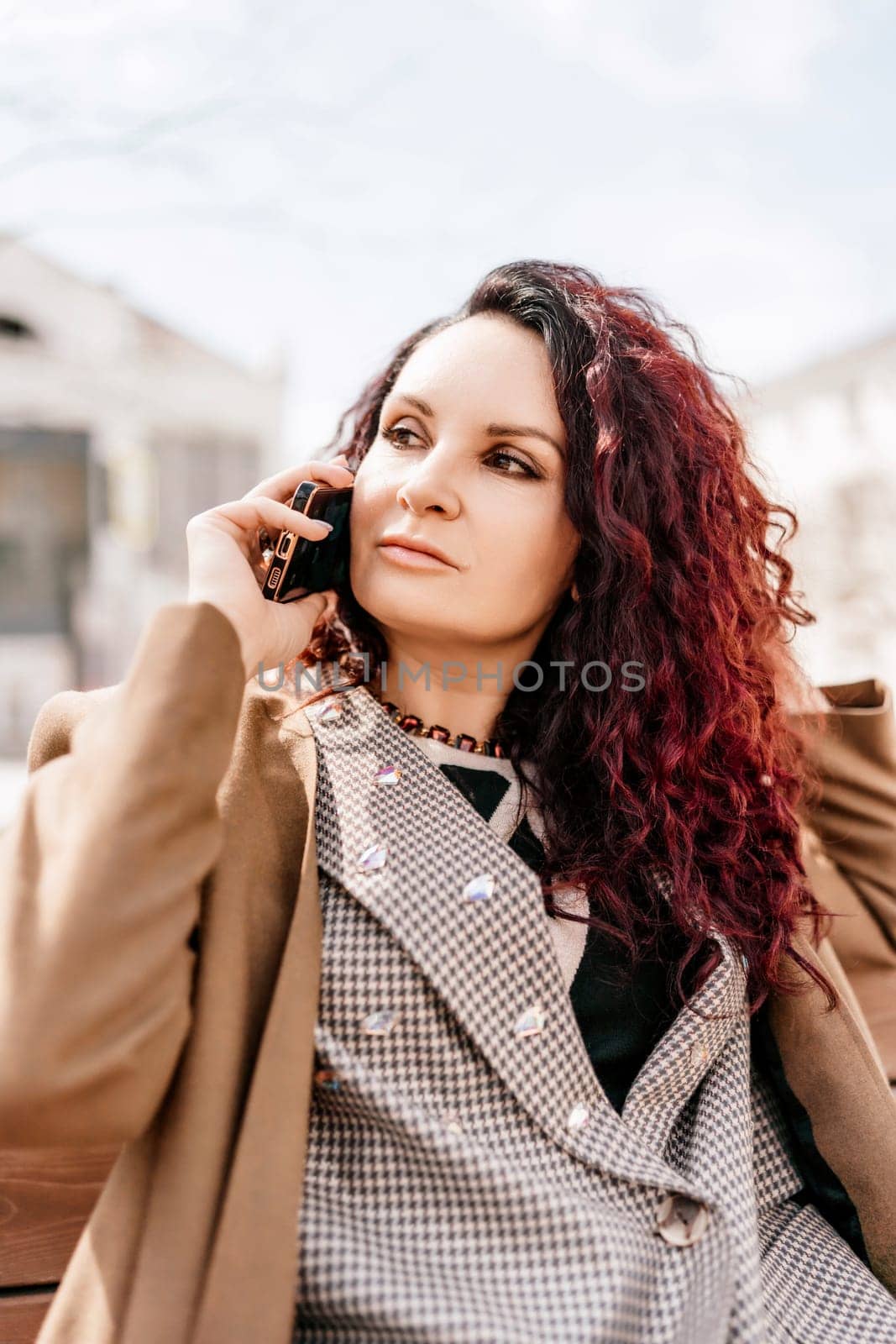 brunette businesswoman talking mobile phone with client. Woman managing business talking via mobile phone sitting by Matiunina