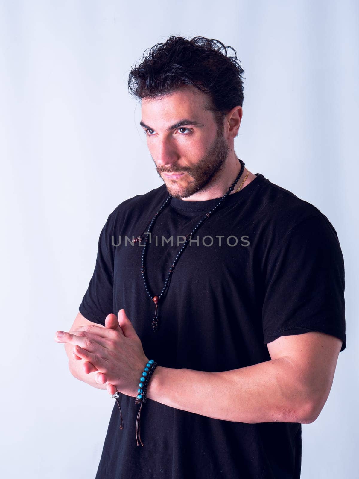 A man in a black shirt is posing for a picture, with hands joined together, on white background