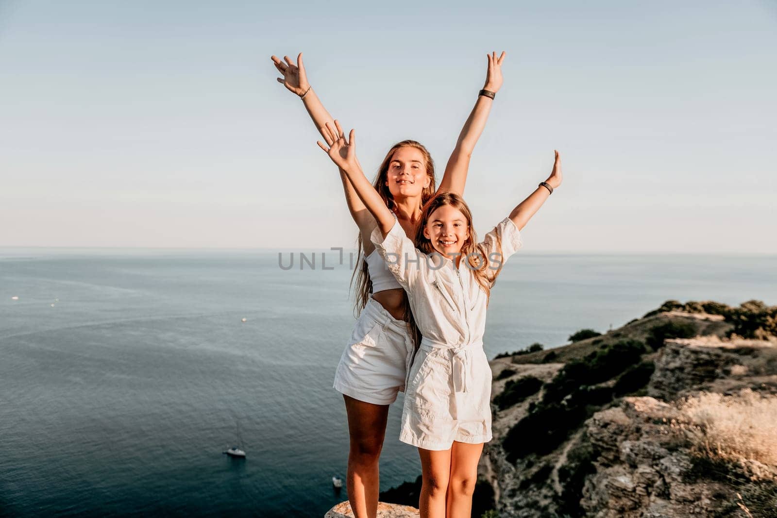 Close up portrait of mom and her teenage daughter hugging and smiling together over sunset sea view. Beautiful woman relaxing with her child.