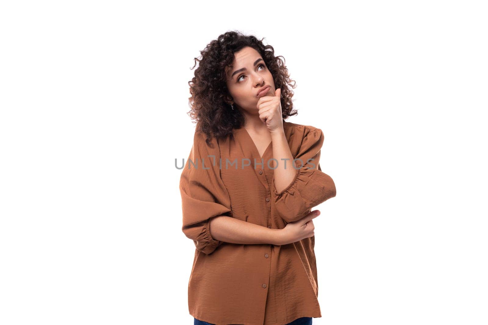 young secretary brunette woman dressed in a brown shirt stands thoughtfully on a white background.