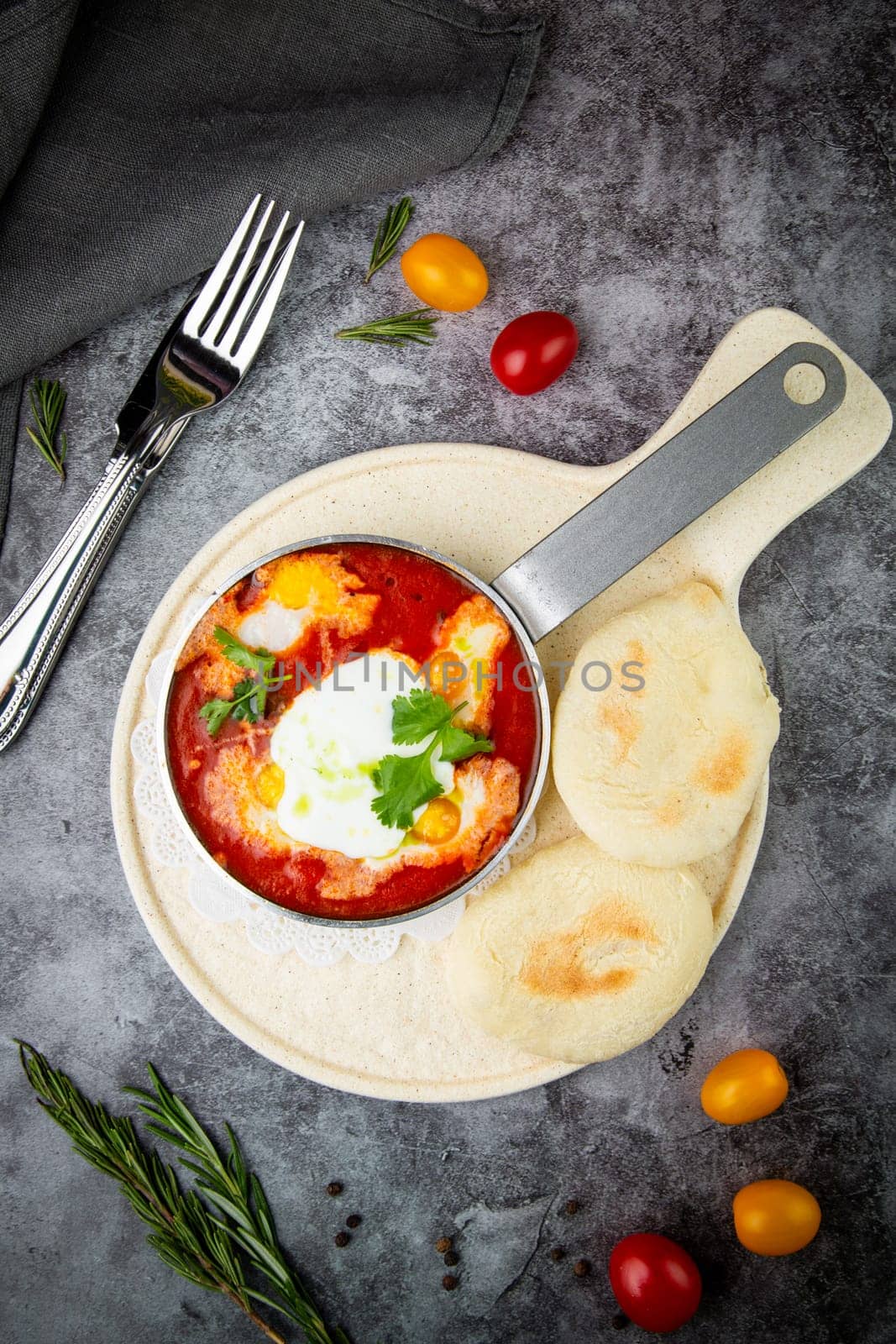 borscht in a frying pan with fresh flatbreads and cherry tomatoes